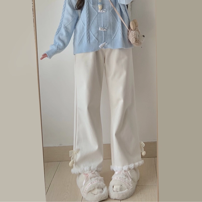 Person wearing a light blue jacket and white pants with decorative elements, standing in front of a mirror.