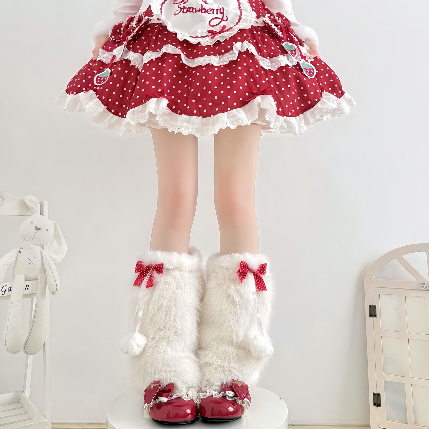 Person wearing a red polka dot dress with white frills and white furry boots with red bows.