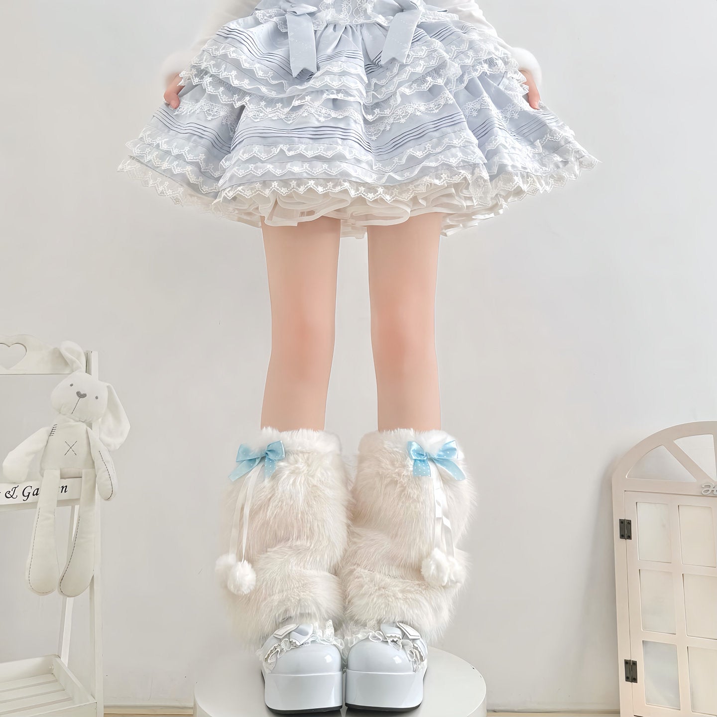 Person wearing a white dress with blue patterns, white knee-high socks with bows, and white shoes in a room.