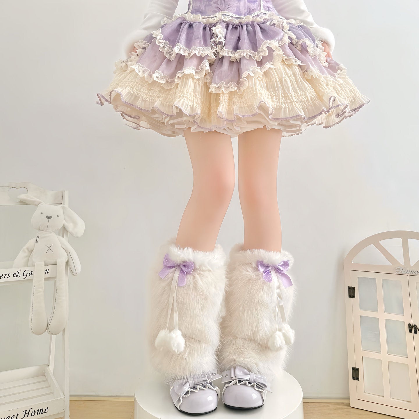 Person wearing a lavender dress with a skirt and white knee-high boots with purple bows in a room.