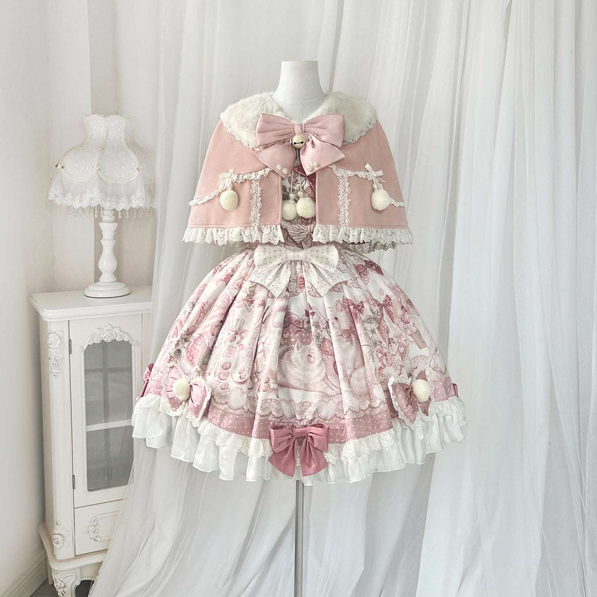 Lolita-style dress with pink floral pattern and white ruffles on a mannequin against a white curtain background.