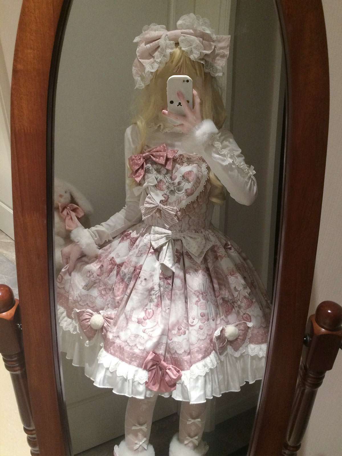 Person wearing a pink and white floral dress with a bow headband in front of a mirror.