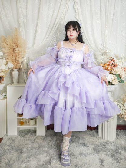 Woman in a lavender dress sitting in a decorated room with flowers and white curtains.