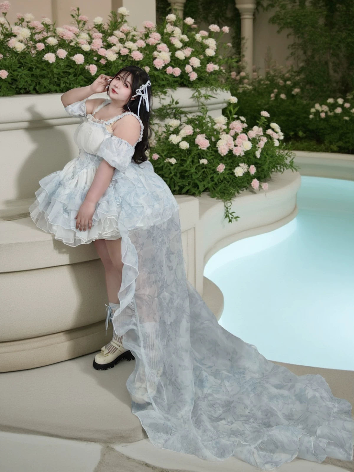 Woman in a white lace dress standing by a pool with floral decorations
