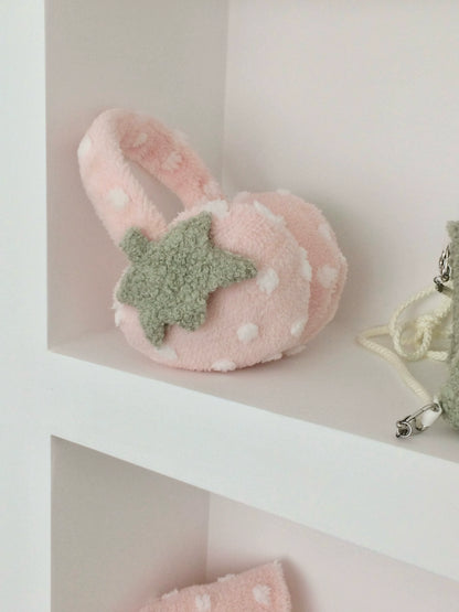 Pink strawberry ear muffs with a green star on a white shelf