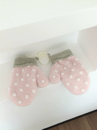 Pair of pink strawberry mittens with white polka dots on a light background