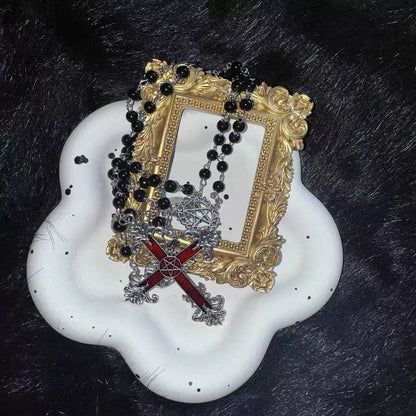 Decorative frame with black beads and a red cross on a white base against a dark background