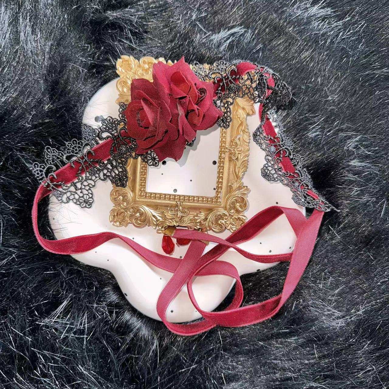 Decorative choker with gold frame, red flowers, and ribbons on a textured black background