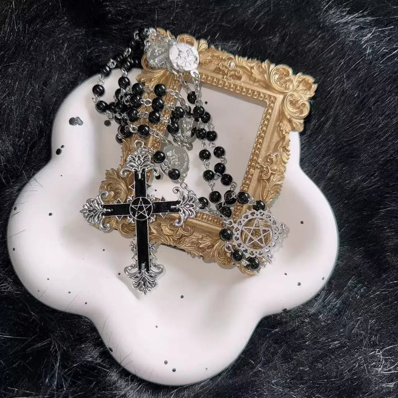 Decorative frame with black and gold rosary on a white dish against a dark fur background
