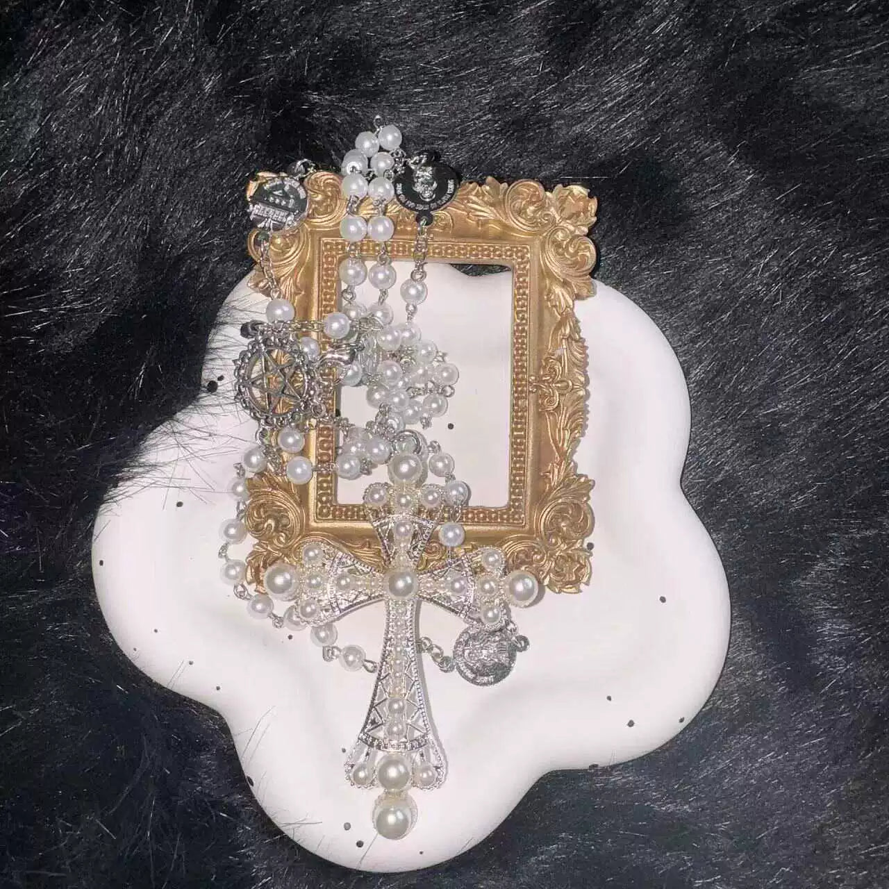 Decorative necklace with gold frame, pearls, and crystals on a black fur background