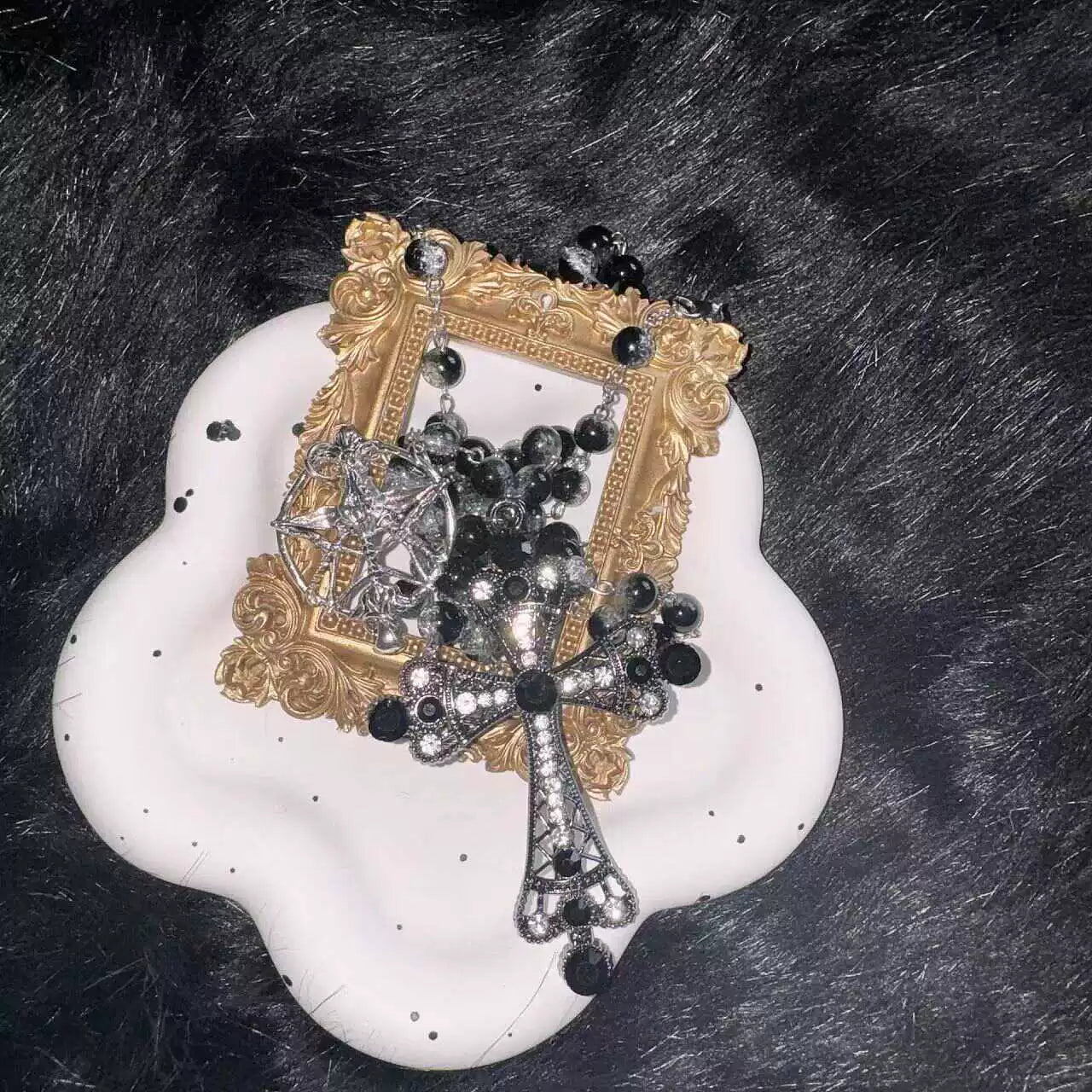 Decorative item with cross-shaped necklace on a white base against a dark background