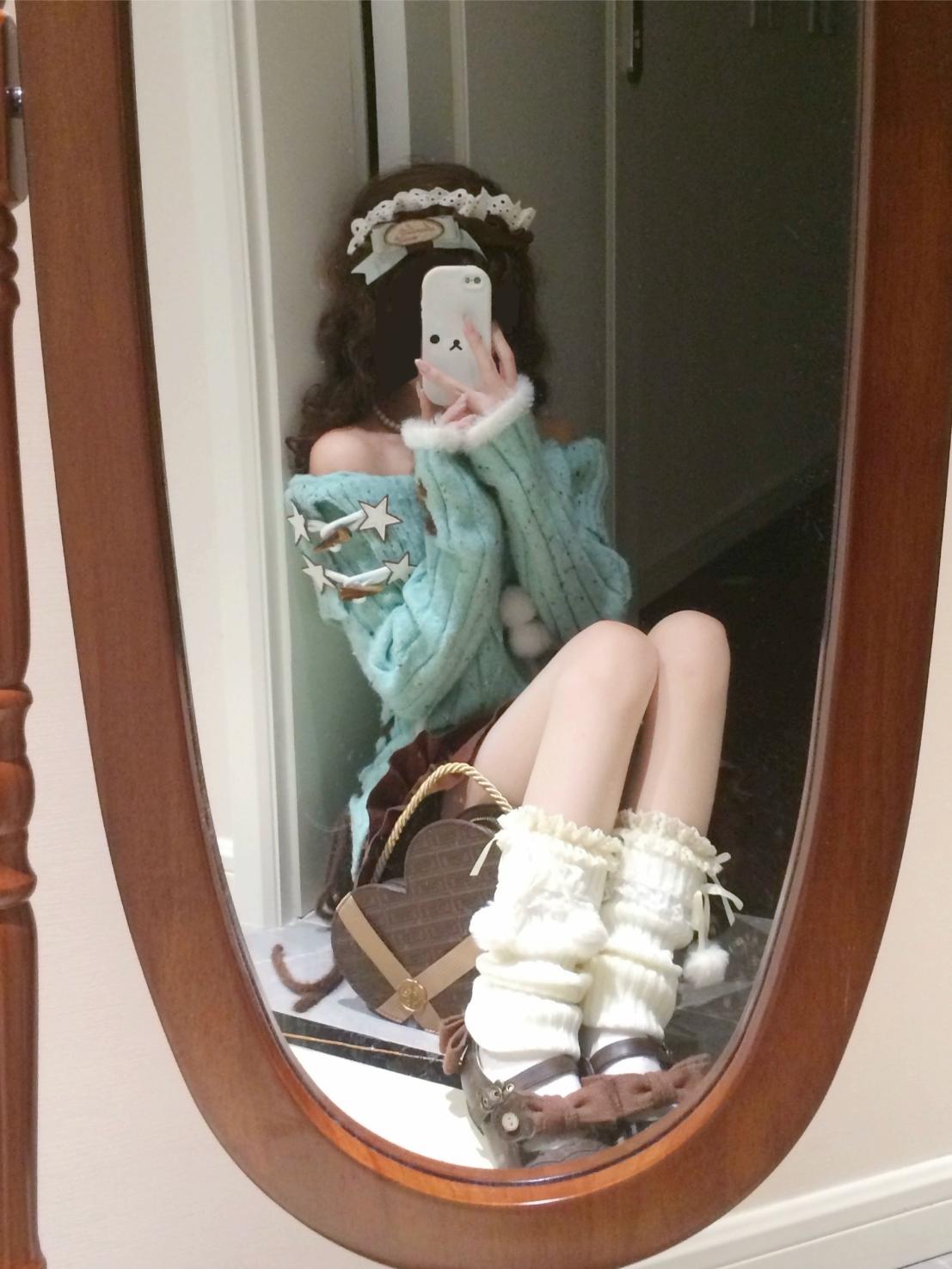 Person wearing a blue sweater and white leg warmers sitting in front of a mirror.