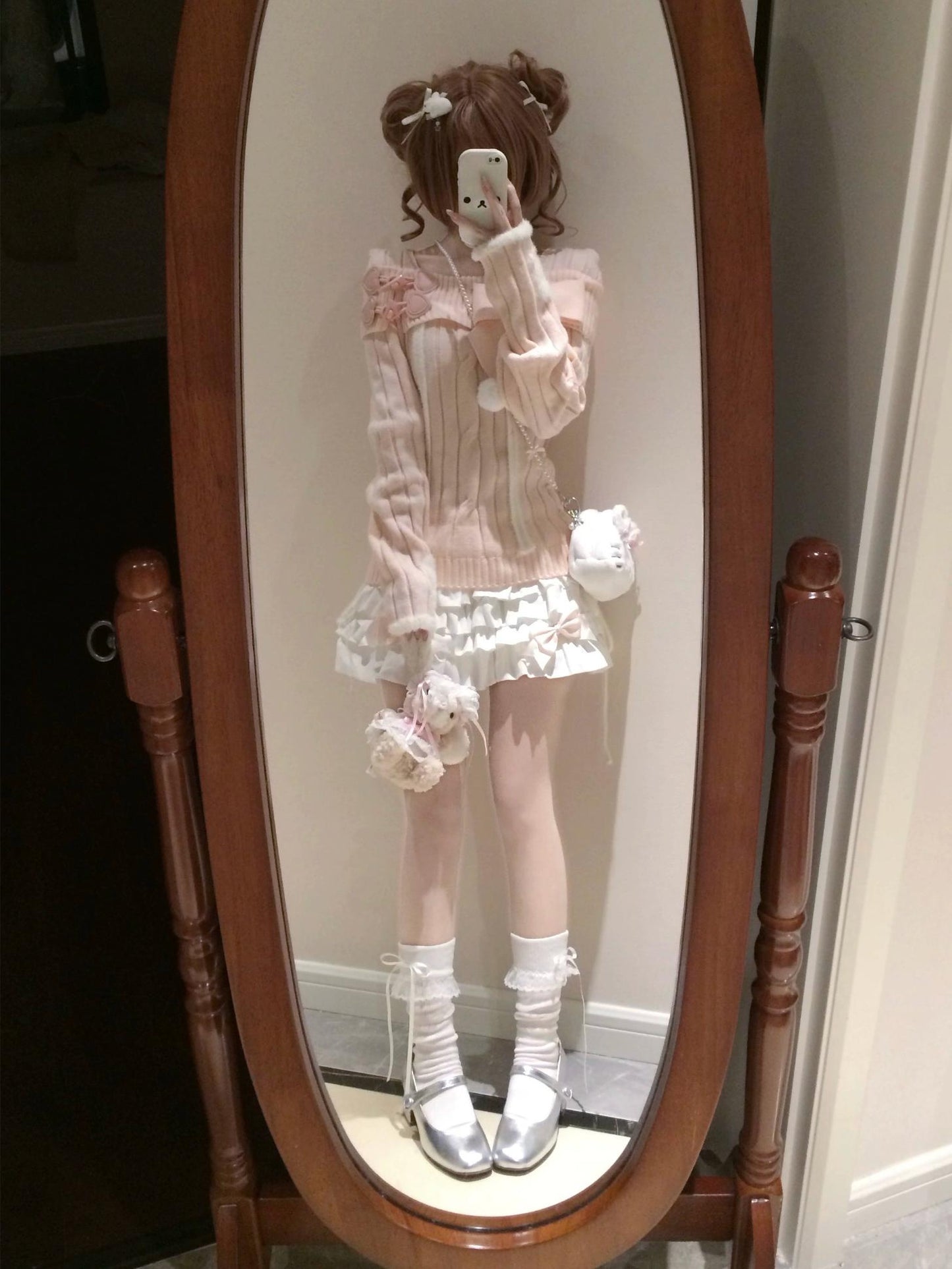 Person wearing a pink outfit with white accents standing in front of a mirror.