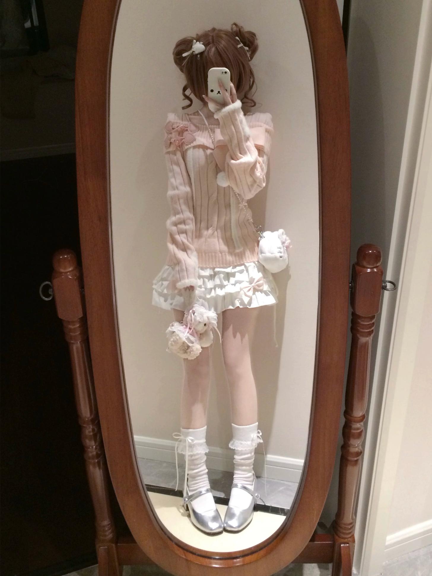Person wearing a pink outfit with white accents standing in front of a mirror.