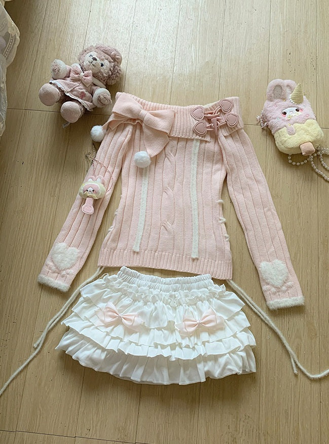 Pink sweater with white ruffled skirt and decorative elements on a wooden floor.