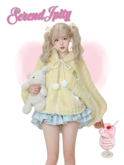 Person wearing a fluffy yellow coat with a pink background and 'Serendipity' text.