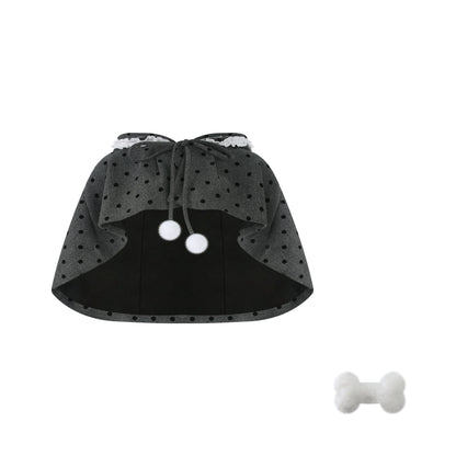 Black cape with white polka dots and a bone-shaped toy on a white background