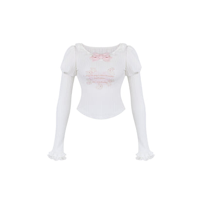 White long-sleeve top with decorative elements on a white background
