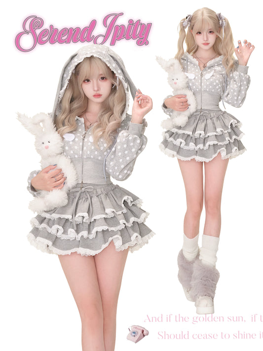 Two people wearing matching gray outfits with white polka dots and frills, holding plush toys.