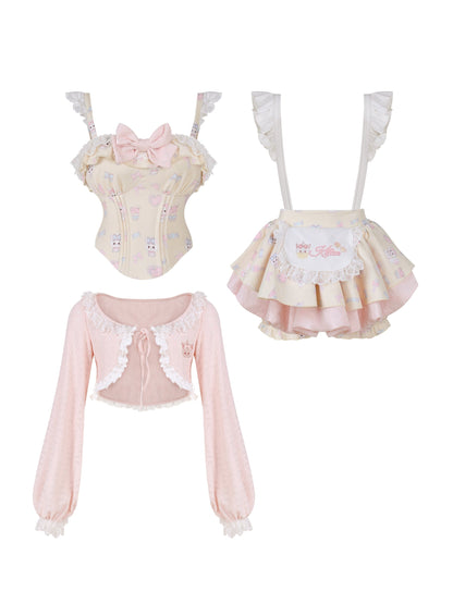 Set of pastel pink and cream Lolita clothing with a top, skirt, and cardigan on a white background.