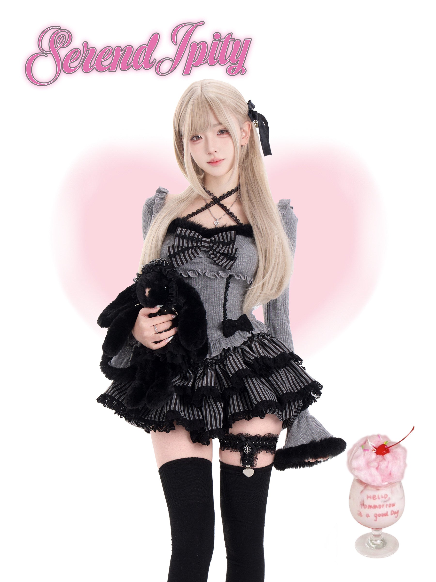 Person in a black and gray outfit with a fluffy black toy, holding a pink dessert with a cherry on top, against a light pink background