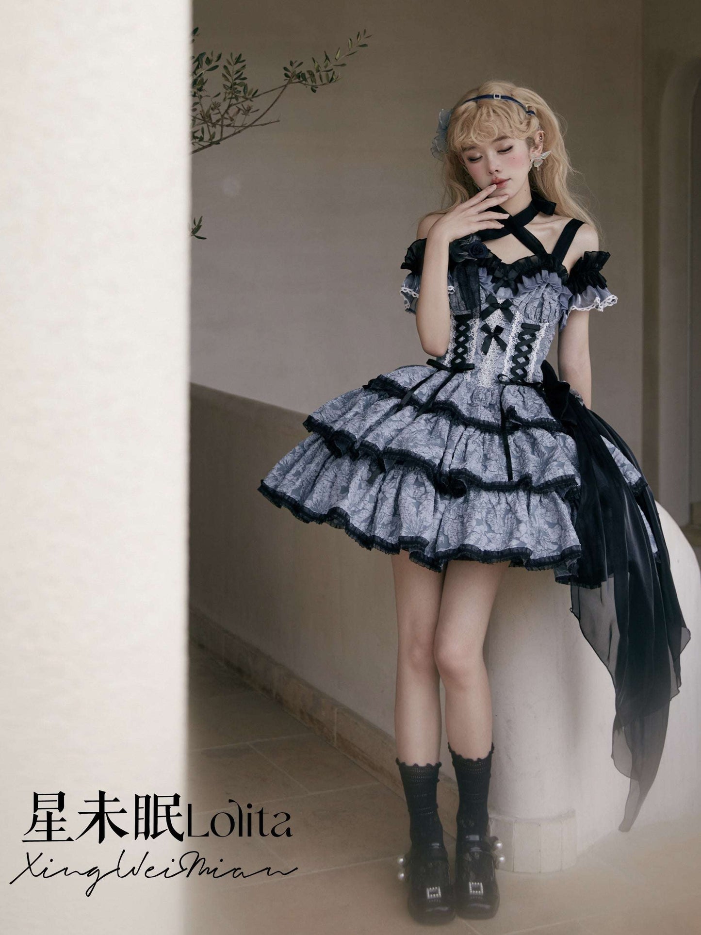 Person wearing a detailed black and white dress with ruffles, standing indoors.