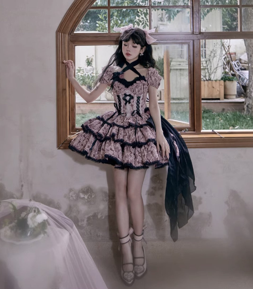 Woman in a stylish dress standing in a room with a window.