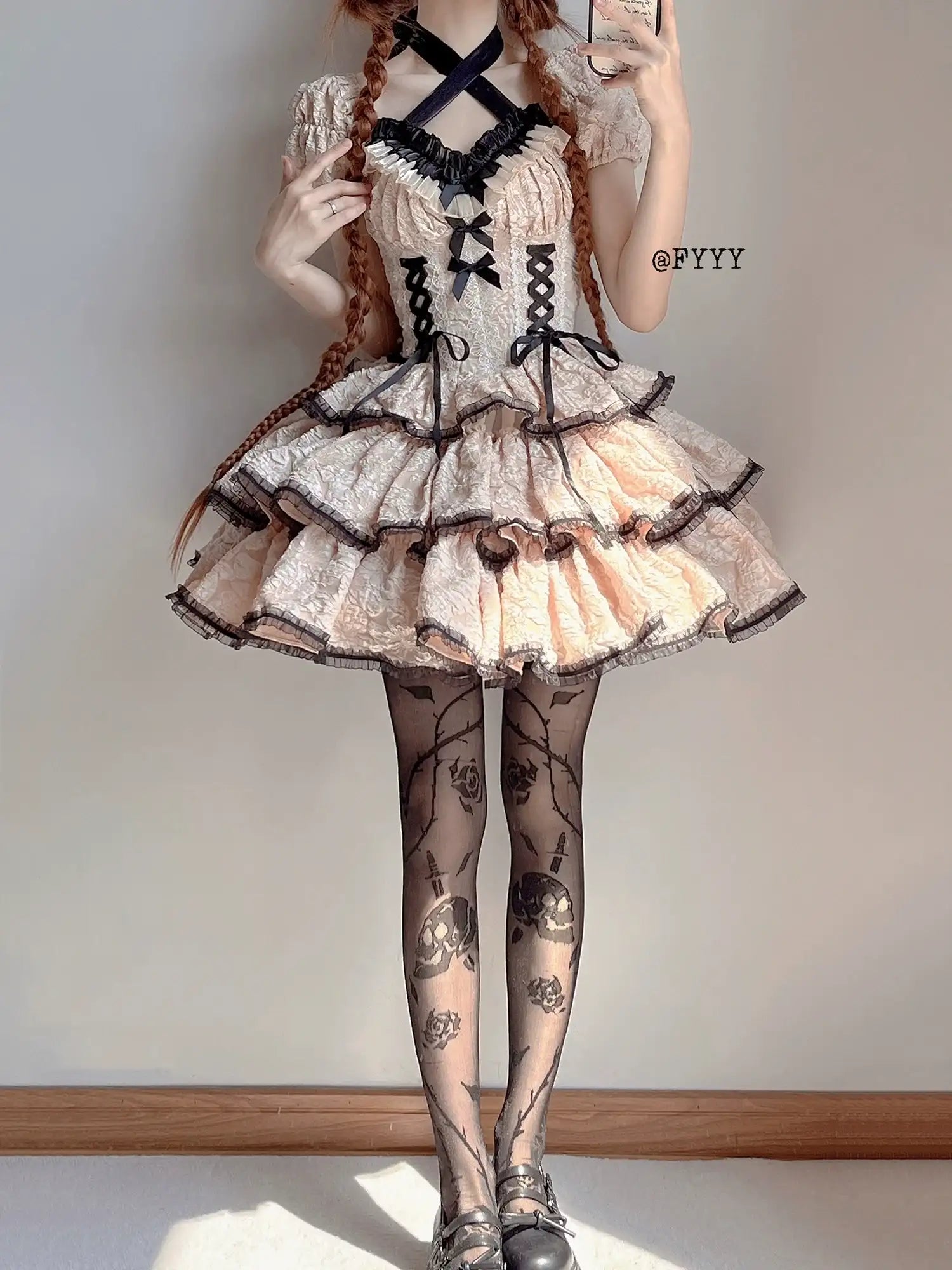 Person wearing a detailed dress with black ribbons and lace, standing against a plain background.