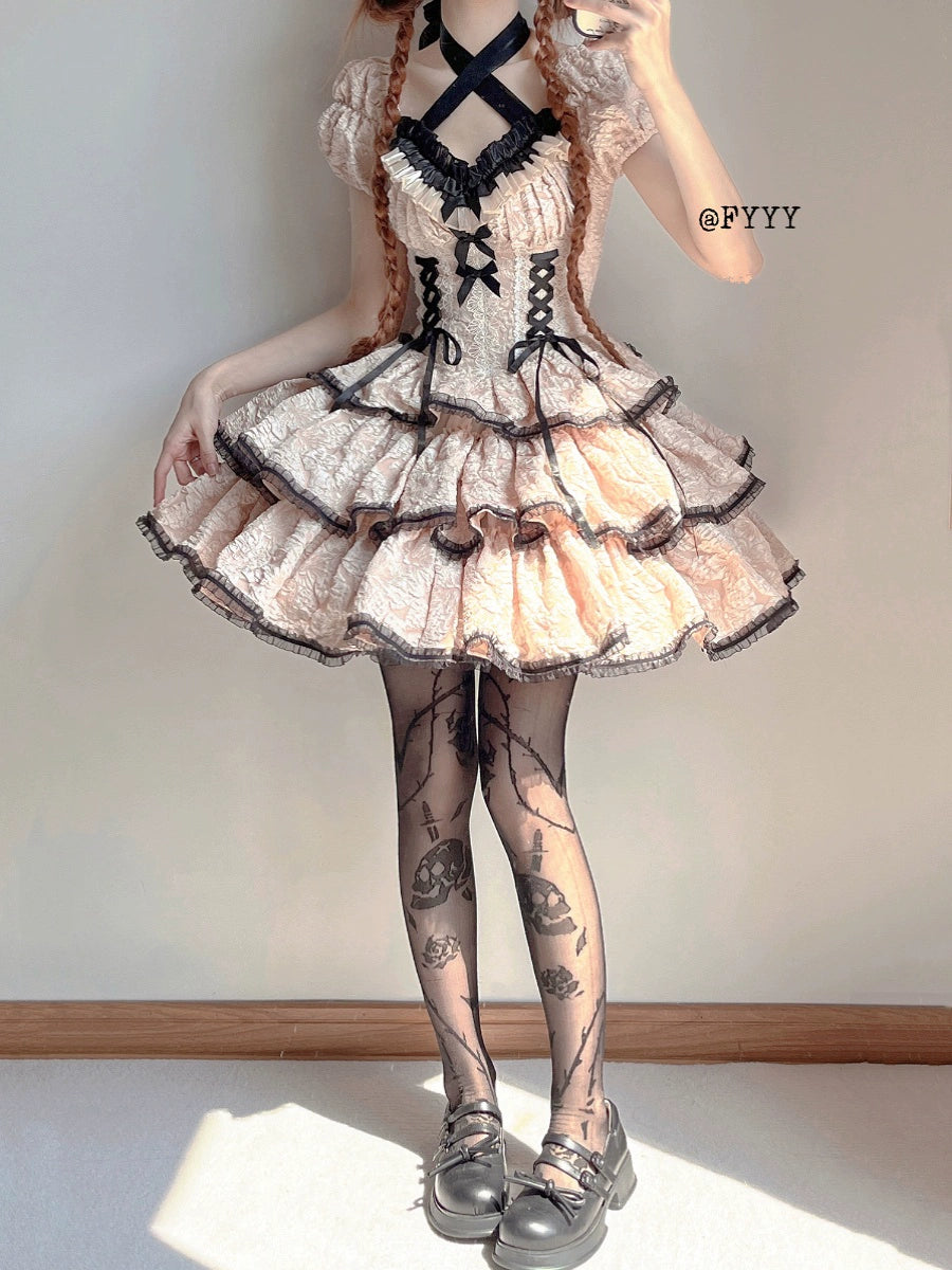 Person wearing a lace dress with black accents and patterned stockings against a plain background