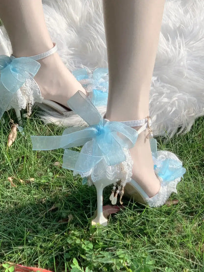 High-heeled shoes with blue ribbons and lace details on a grassy background
