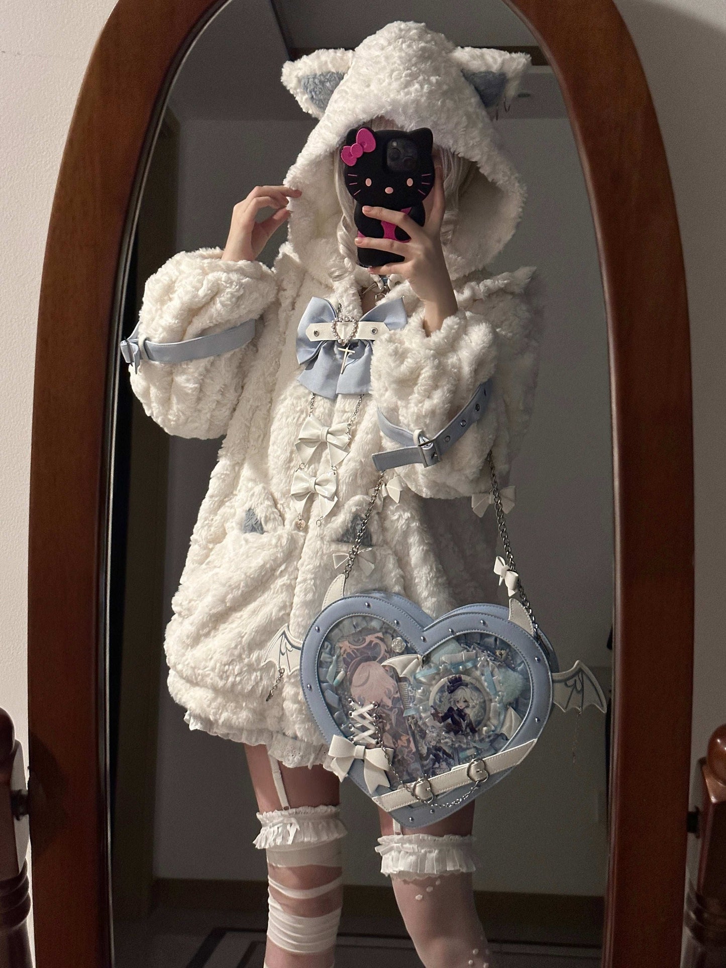 Person wearing a fluffy white costume with a large bow and heart-shaped bag, standing in front of a mirror.