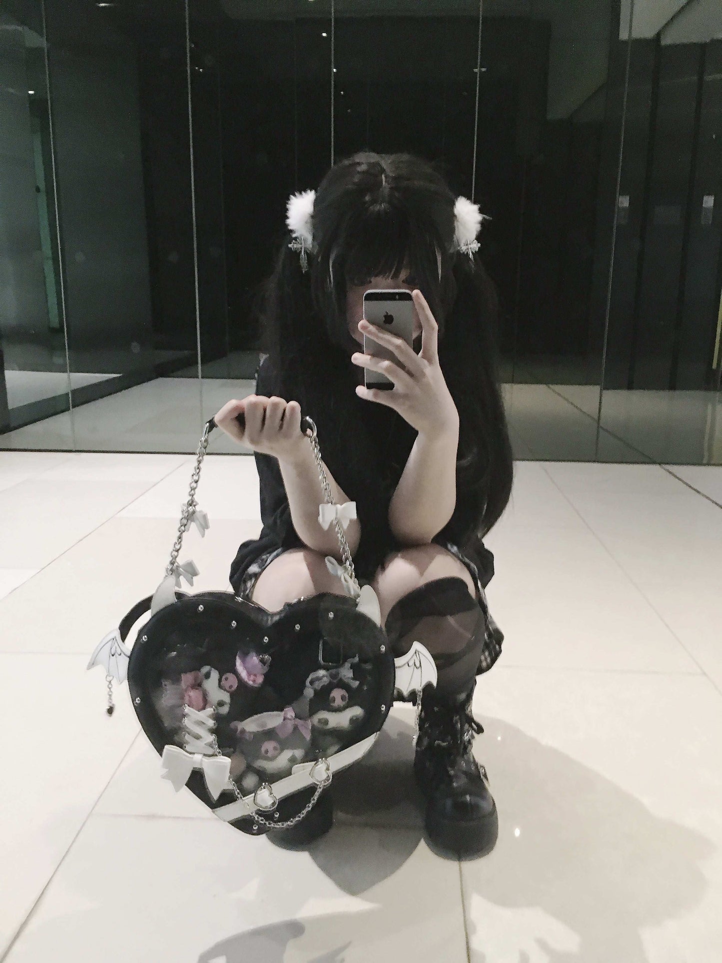 Person holding a heart-shaped bag in a reflective indoor setting