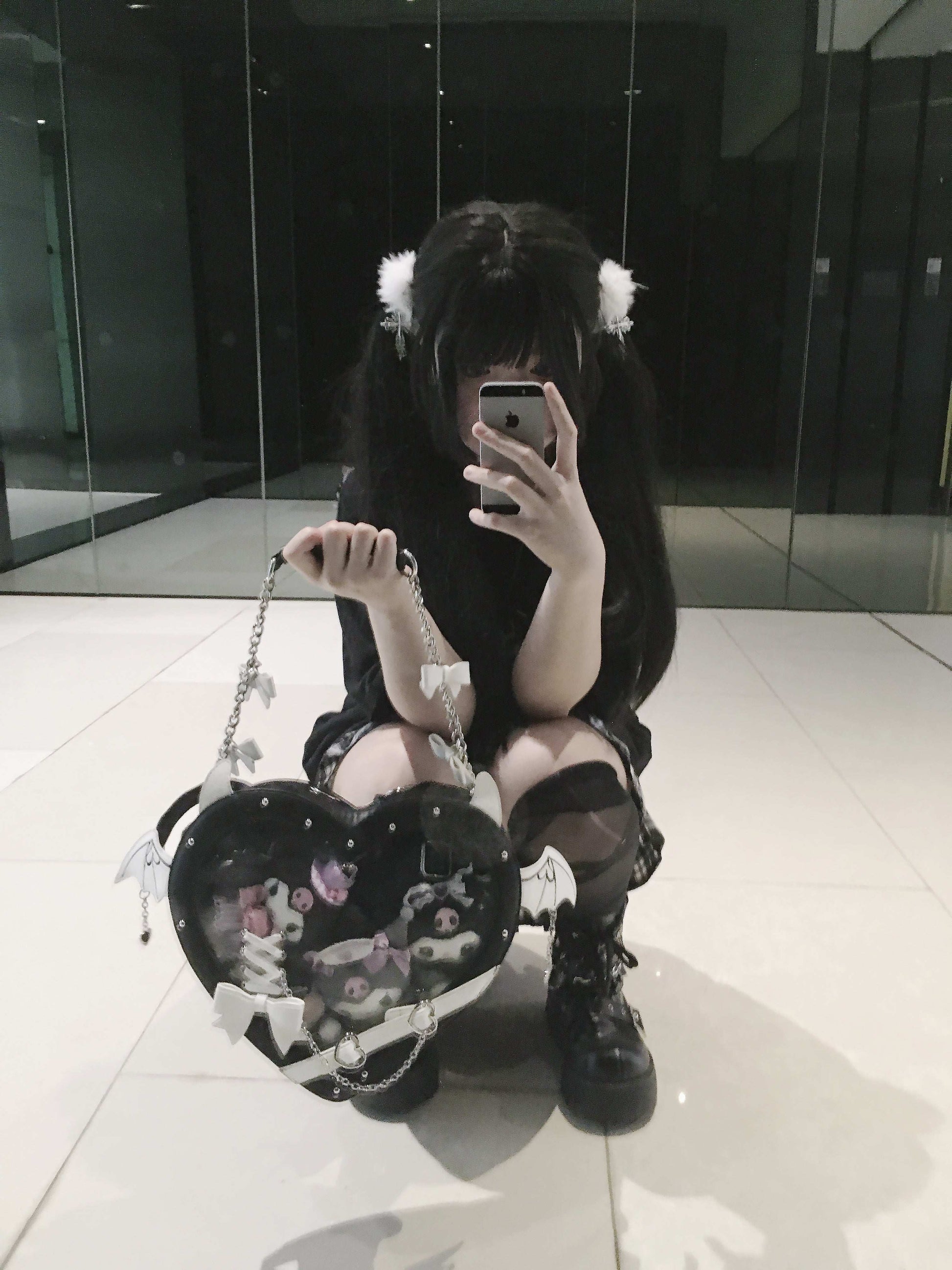 Person holding a heart-shaped bag in a reflective indoor setting