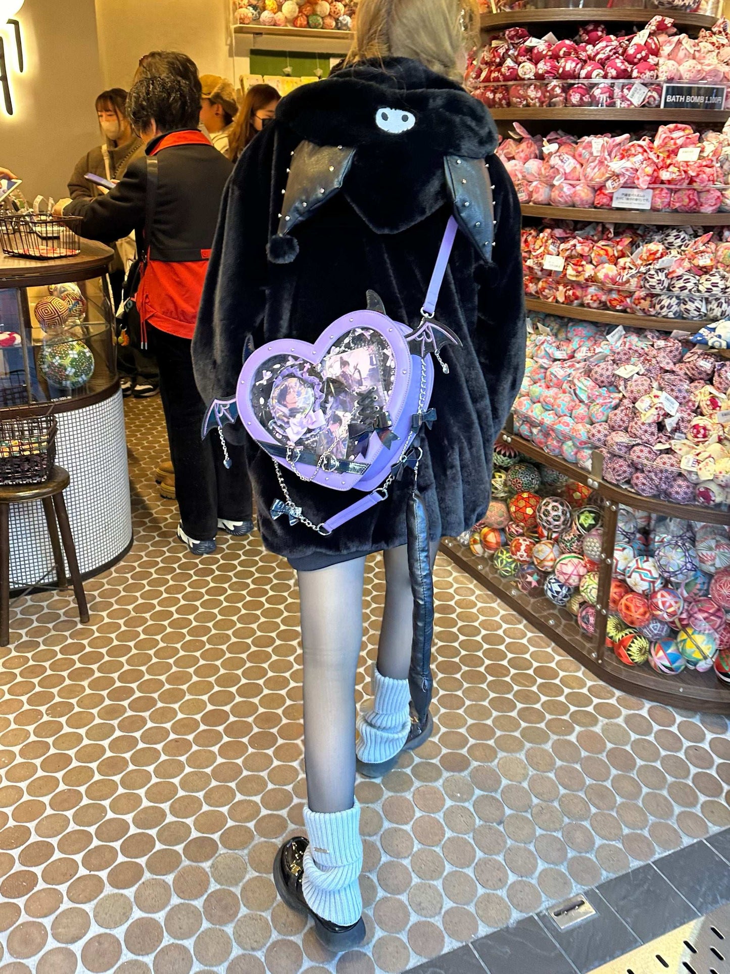 Person wearing a black coat with a heart-shaped design in a candy store