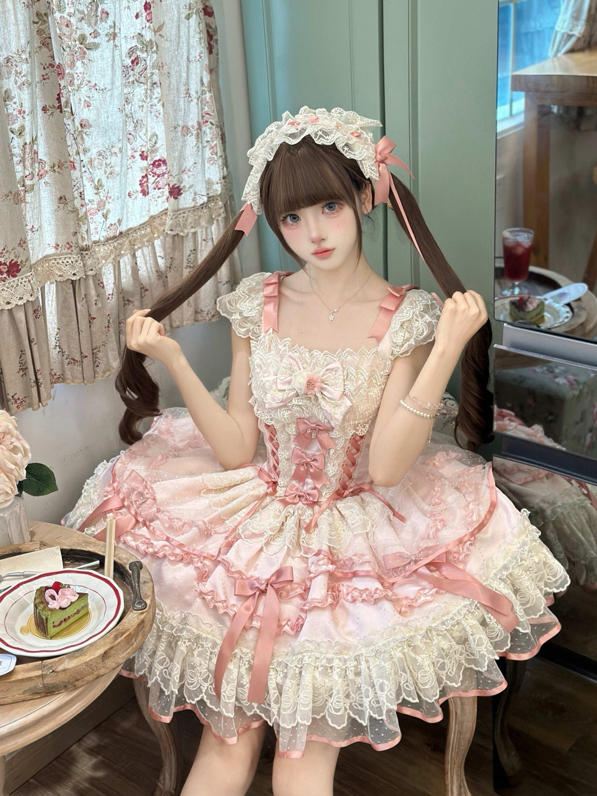 Person wearing a pink and white Lolita-style dress sitting in a room with floral curtains.