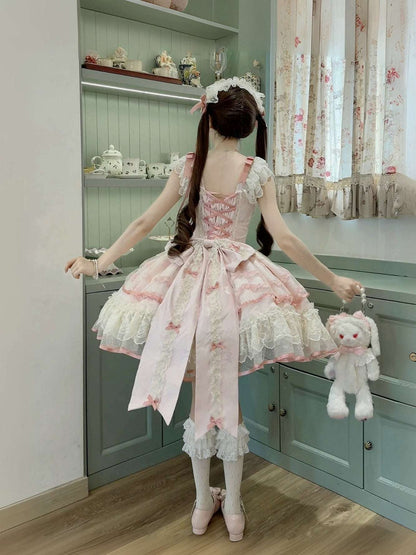 Person wearing a pink and white dress with a teddy bear in a room with green cabinets and floral curtains.