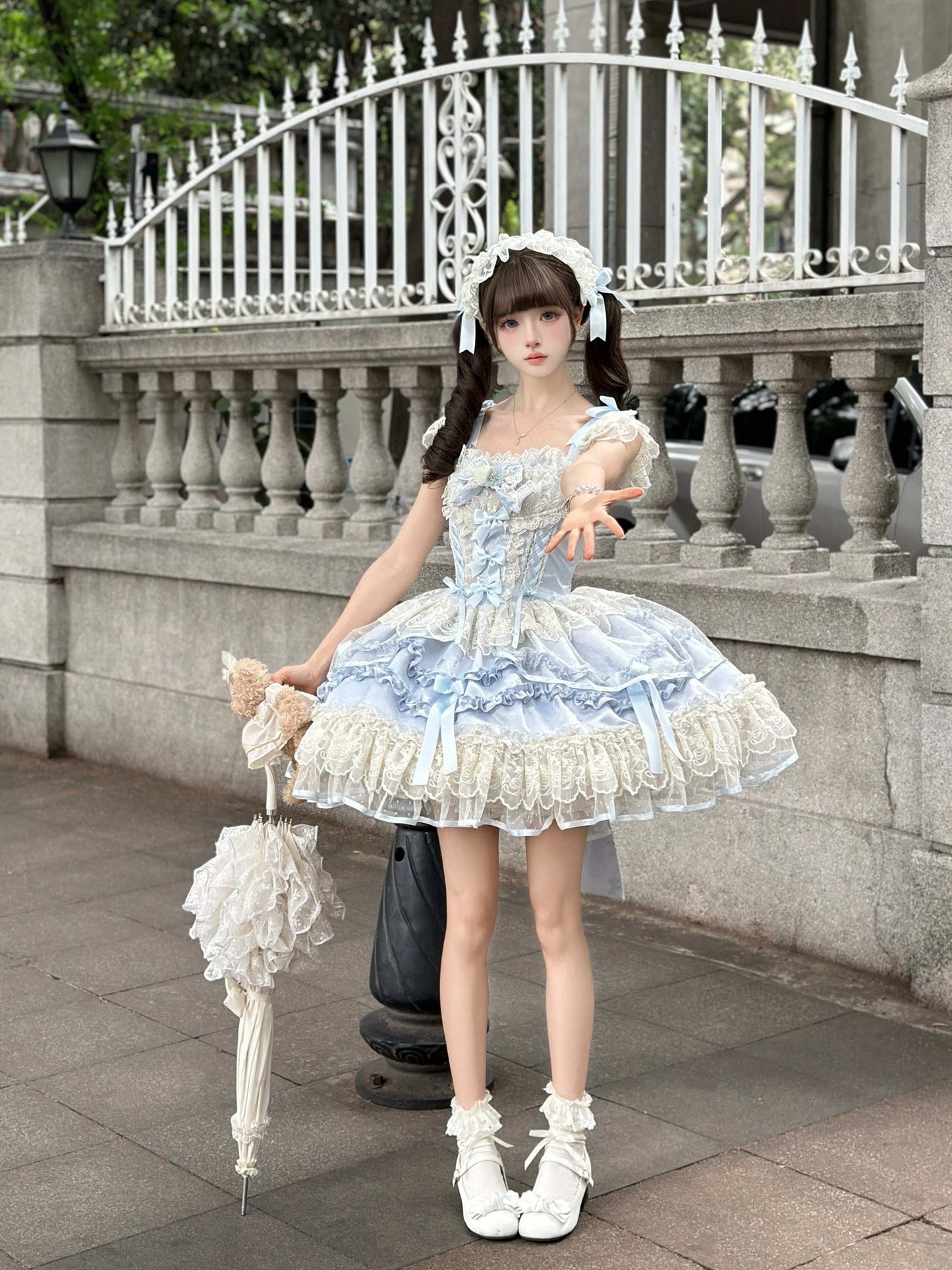 Woman in a light blue and white dress standing outdoors with decorative elements.