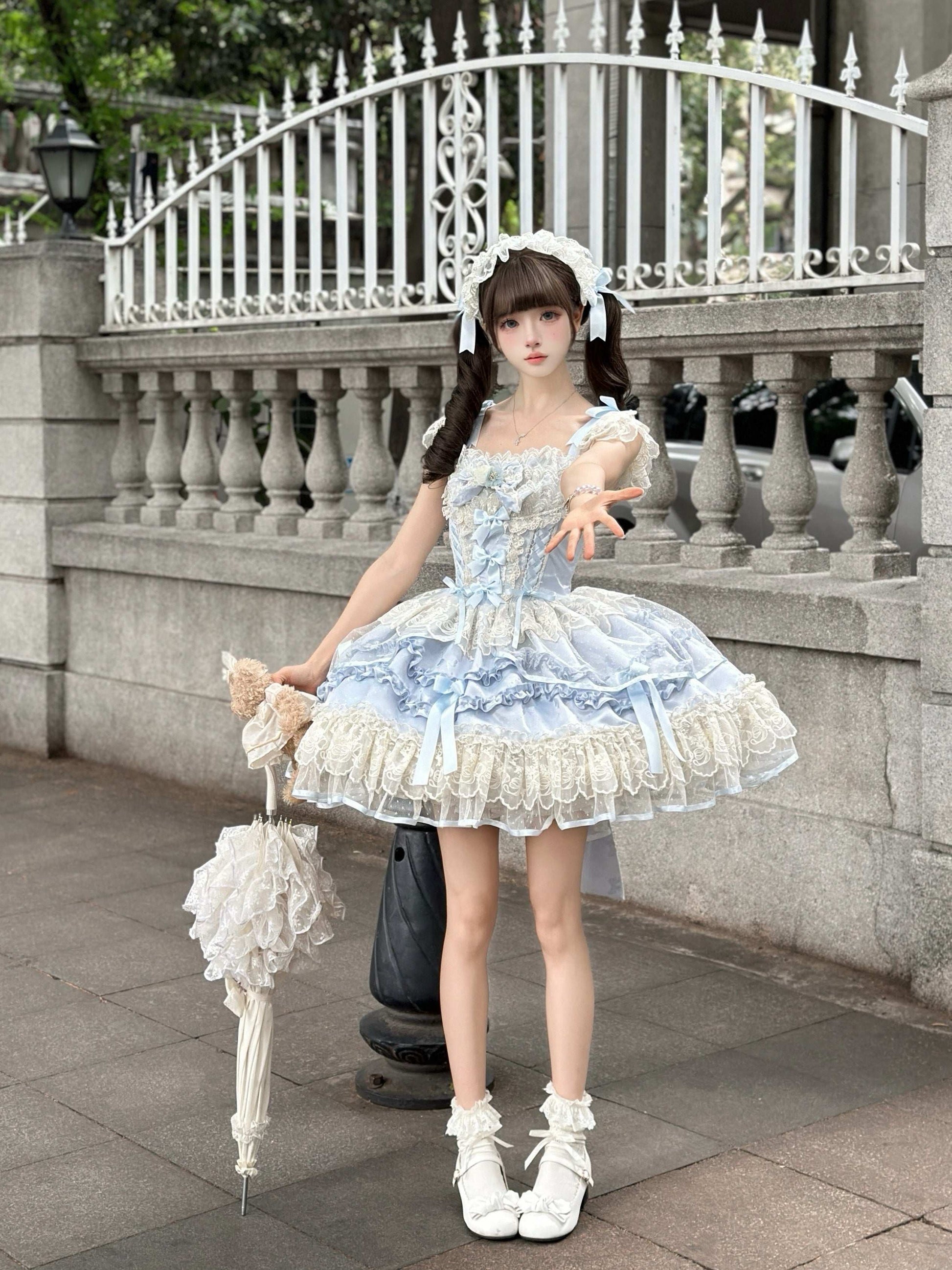 Woman in a light blue and white dress standing outdoors with decorative elements.