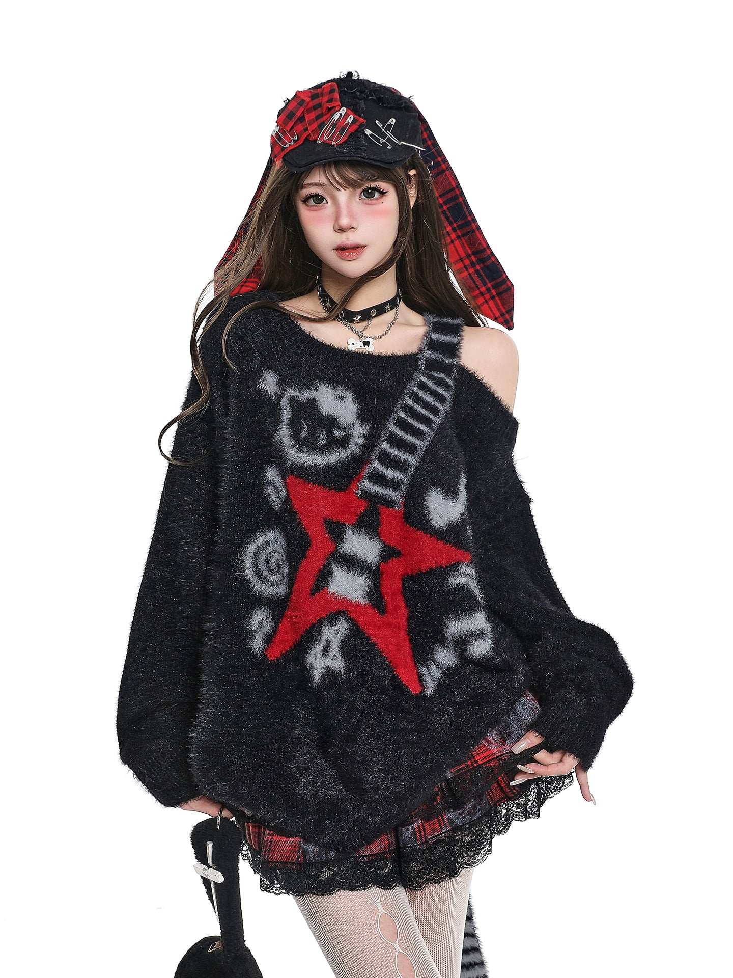 Person wearing a black sweater with a red star design and plaid hat on a white background