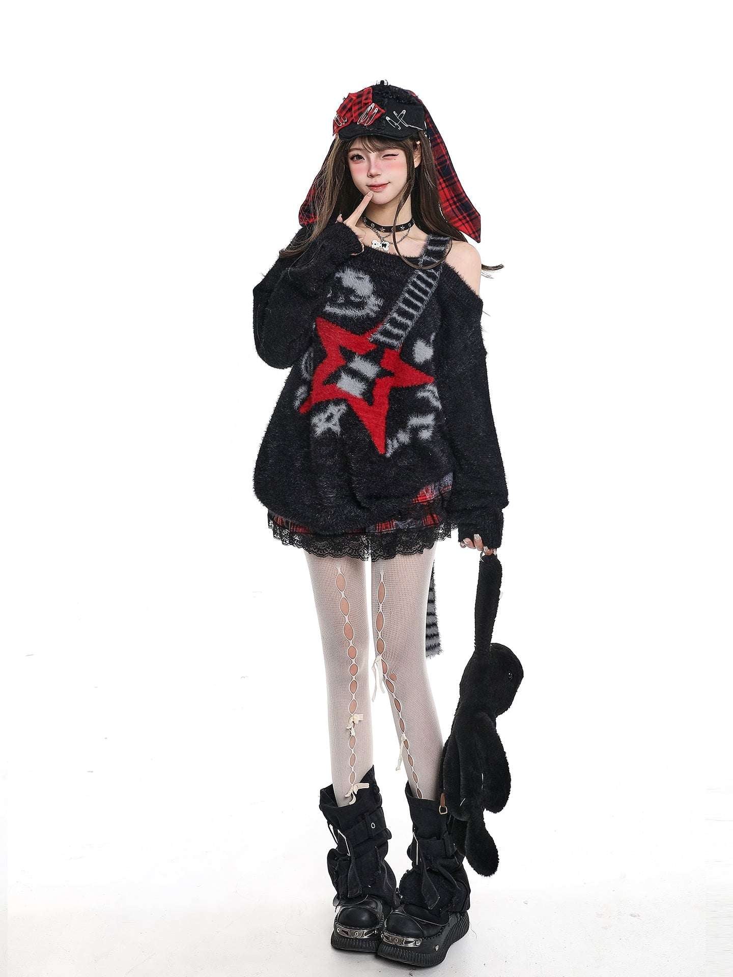 Person wearing a black outfit with red star design, holding a guitar, on a white background