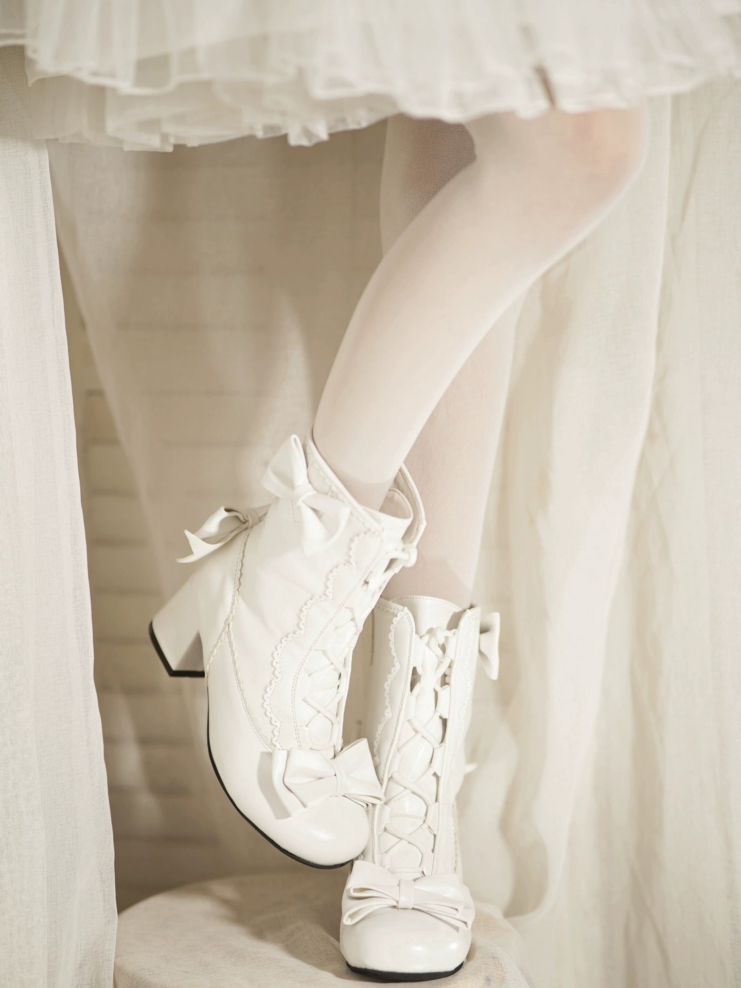White lace-up shoes worn with a white dress and sheer stockings.