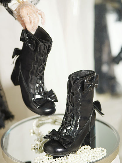 Black high-heeled boots with bow details on a reflective surface.