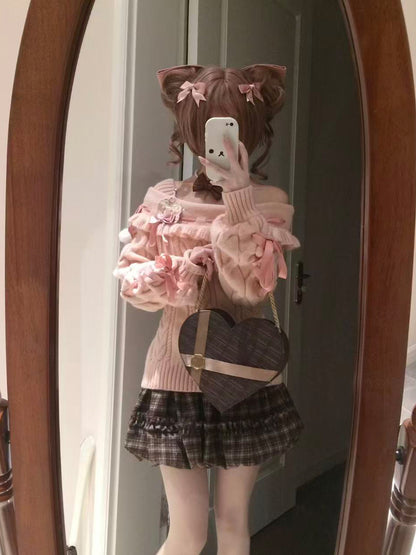 Person wearing a pink sweater and plaid skirt with a heart-shaped bag, standing in front of a mirror.