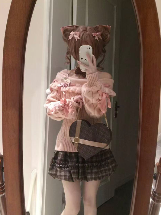 Person wearing a pink sweater and plaid skirt with a heart-shaped bag, standing in front of a mirror.