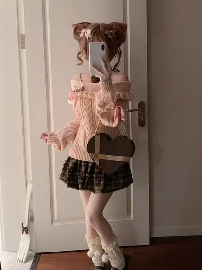 Person taking a mirror selfie wearing a pink sweater, plaid skirt, and white socks.