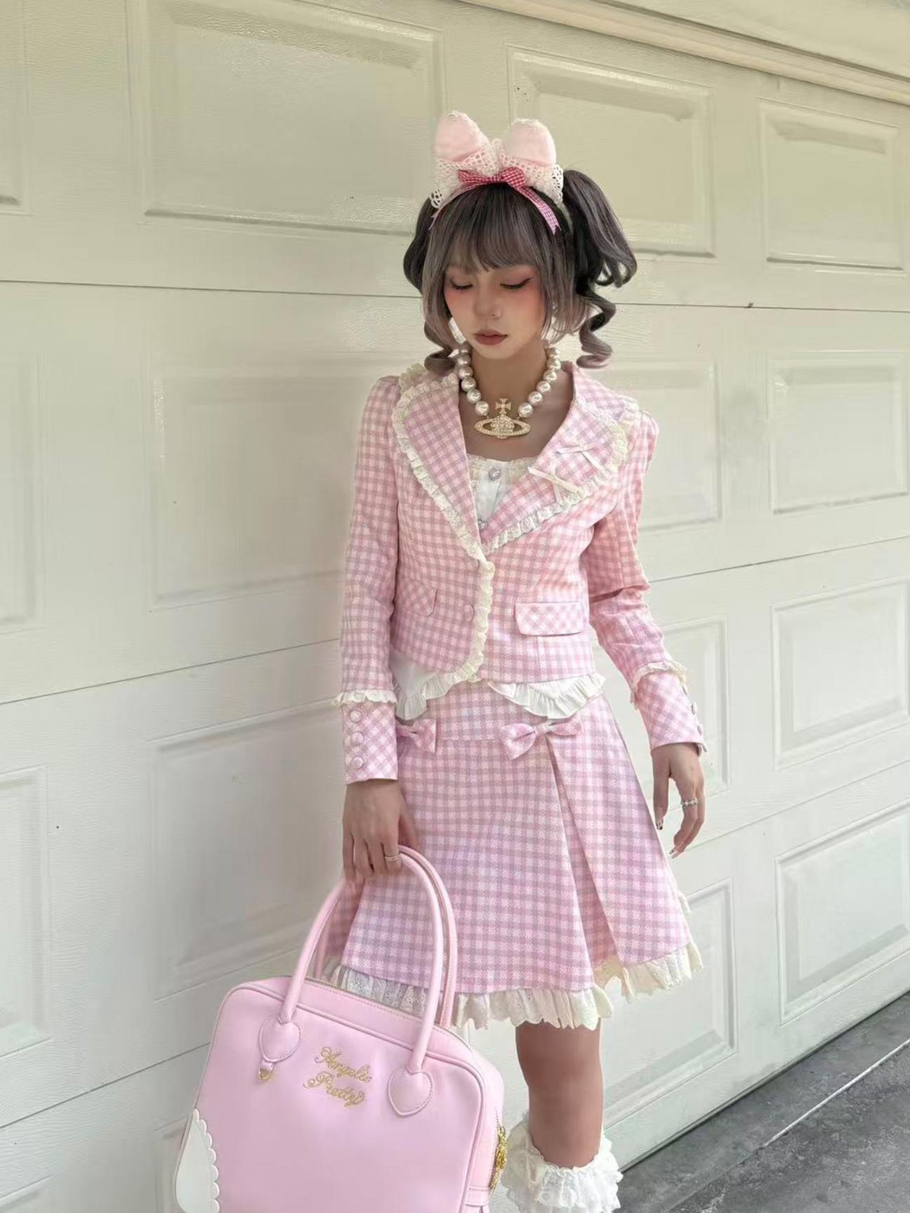 Person wearing a pink checkered outfit with a large bow and holding a matching handbag against a white wall.