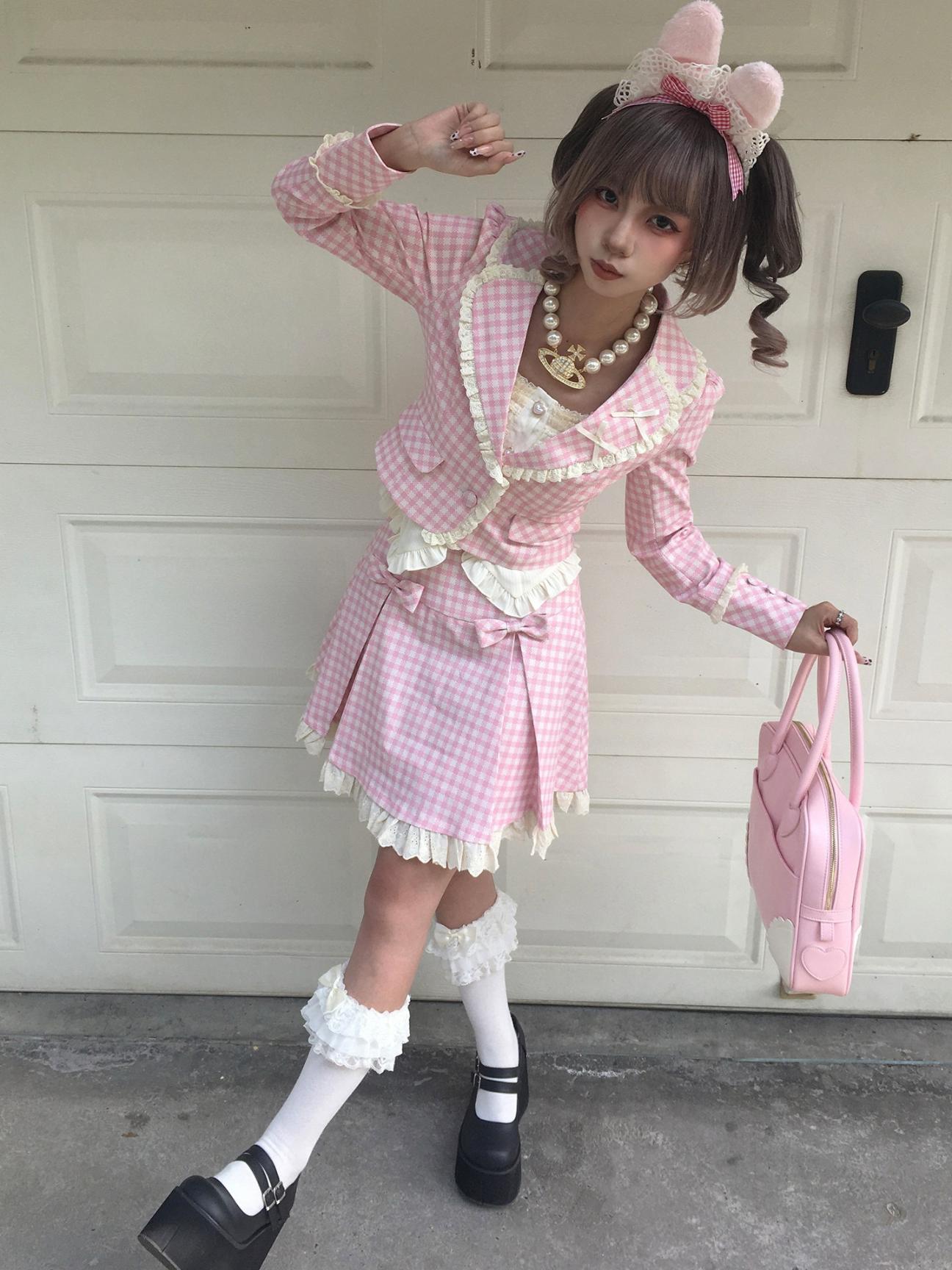 Person in a pink checkered outfit with a headband and white shoes, standing in front of a white door.