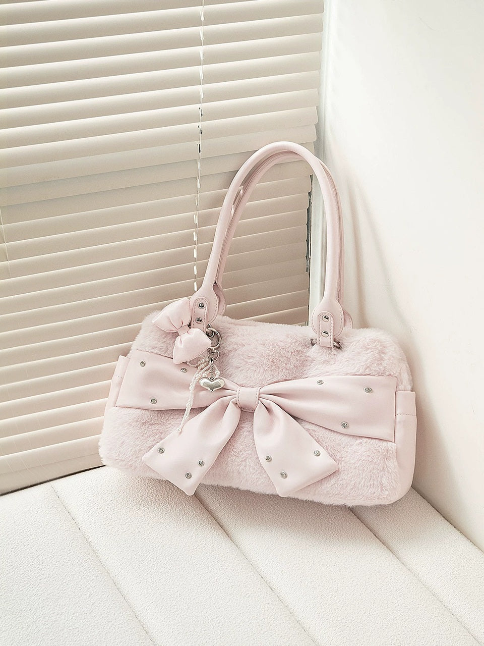 Pink handbag with a large bow on a white surface
