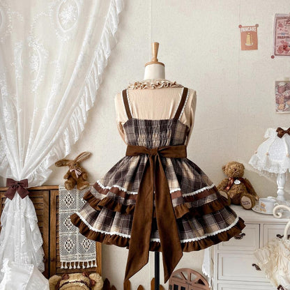 Plaid dress with a large brown bow on a mannequin against a decorative room background.