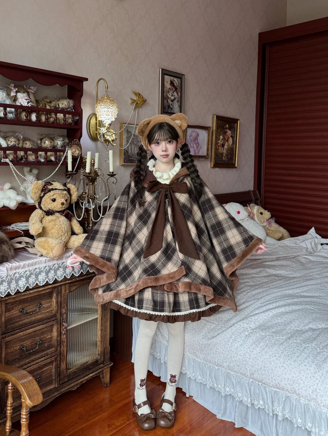 Person wearing a plaid cape and bear ears in a room with decorative items.